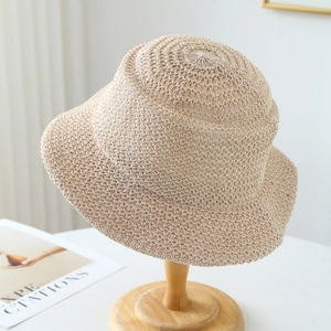 Beige crochet woven bucket hat with minimalist wide brim on a wooden stand