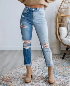 Dettaglio dei jeans a vita alta consumati con design asimmetrico blu a blocchi di colore