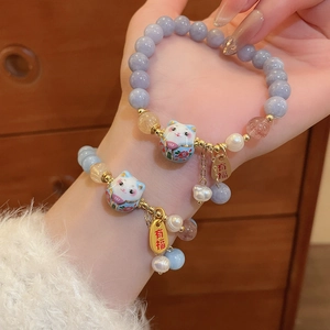 Detail of beaded Maneki Neko bracelet with freshwater pearls and lucky gold charm