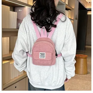 Close-up of pink corduroy mini backpack texture with white FASHION woven label