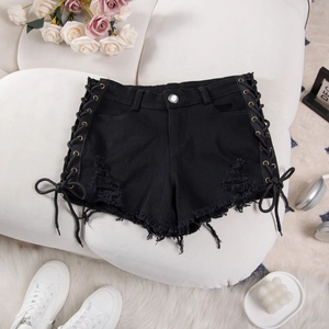 Dettaglio degli shorts di jeans neri con lacci laterali e orli sfrangiati strappati