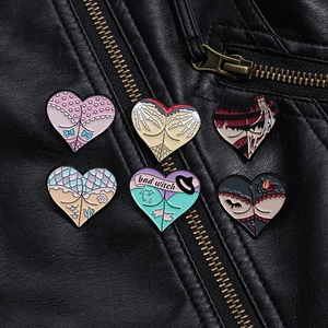 Close-up of six unique gothic heart enamel pins on a black leather jacket texture