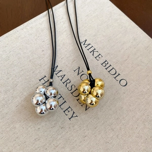 Dettaglio di pendenti a grappolo di sfere in oro e argento con cordini neri fini