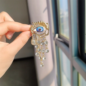 Vintage golden baroque brooch with blue evil eye design and sparkling rhinestone tassels