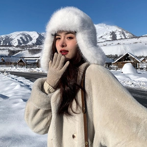 Close-up of white plush trapper hat and beige faux fur coat in snowy mountains