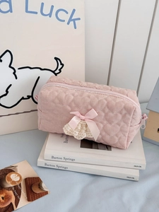 Detail of pink heart-quilted makeup bag with silk bow and delicate lace trim decor