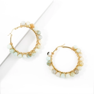 Detailed macro view of handmade gold wire-wrapped hoop earrings with natural stone beads