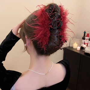 Detail of red feather hair claw clip with black beads worn on an elegant updo