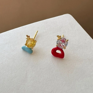 Detail shot of asymmetric stud earrings with colorful zircons and butterfly accents.