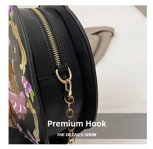 Detail shot of floral embroidery and high-quality gold hardware on black leather bag