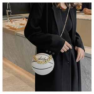 Detail of a white basketball-shaped crossbody bag with gold chain and black stripes