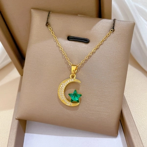 Macro shot of gold moon and star pendant with white diamonds and green gemstone