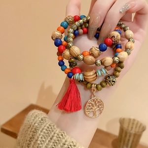 Detail of Bohemian multilayer sandalwood beads with a tree of life charm and red tassel