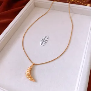Macro detail of 18k gold plated croissant moon pendant on a polished box chain
