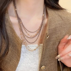 Close-up of multi-layer crystal beaded necklace with gold chains on a fashion model