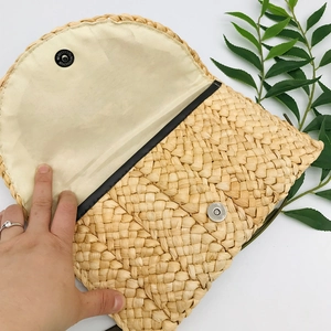 Handmade woven corn husk clutch bag with magnetic closure and beige fabric lining