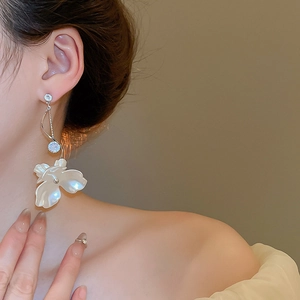 Détail de boucles d'oreilles fleurs en argent avec pétales blancs et pompon cristal
