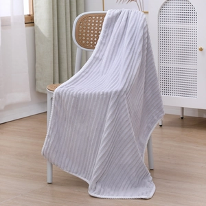 Detailed view of grey striped coral fleece towel set draped over a white chair