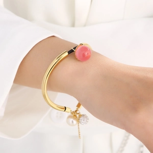 Detail of elegant gold bead bracelet with pink resin and pearl on model wrist