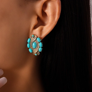 Close-up of vintage gold bohemian earrings with turquoise stones and shimmering rhinestones