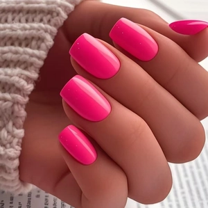 Macro detail of glossy rose pink press-on nails in square-oval shape with knit sweater background