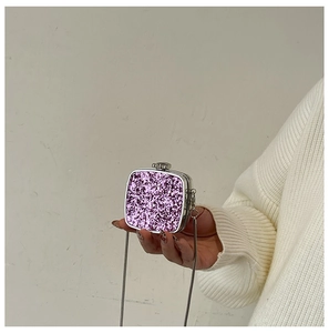 Close-up of a purple sequin mini evening bag with a silver chain held by a person