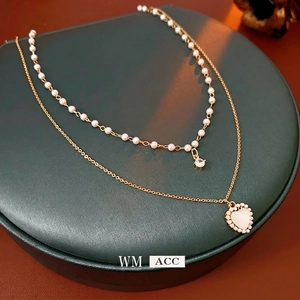 Double-layered gold necklace featuring heart opal pendant and elegant pearl accents