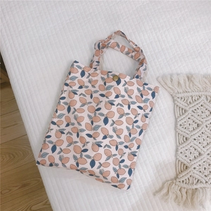 Détail d'un sac cabas en toile fleurie avec motif citron et fermoir pression en métal bronze