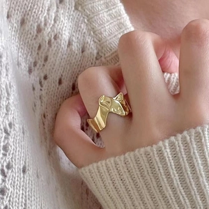 Irregular textured gold open ring with lava design on a hand over a knit sweater