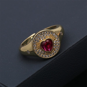 Vue macro d'une bague dorée avec pierre en cœur rouge rubis et double halo serti