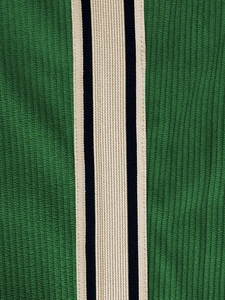 Vue macro détaillée du tissu en velours côtelé vert forêt avec bande latérale rayée noir et blanc