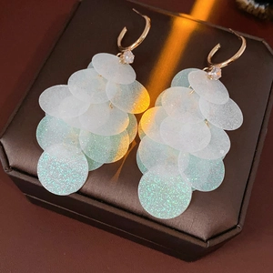 Macro view of C-shaped tassel earrings with white sequins and sparkling zircon accents
