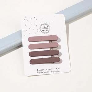 Close-up of four matte brown and pink hair clips arranged on a white display card