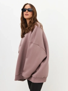 Detail of drop shoulder seams and ribbed cuffs on oversized fleece sweatshirt