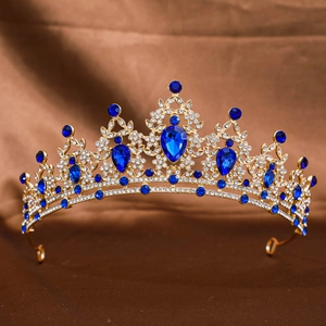 Detail of gold crown featuring large blue teardrop gems and sparkling white rhinestones