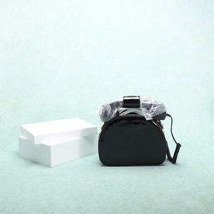 Close-up of creative telephone-shaped black handbag with glossy finish and spiral cord detail