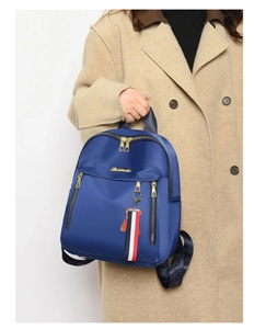 Detail of navy blue oxford backpack with gold zippers and decorative bear charm