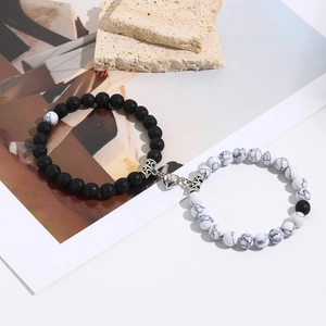 Detail of couple magnetic bead bracelets with black lava and white marble stone hearts