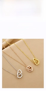 Close-up of interlocking heart pendants in silver, gold, and rose gold with zircon