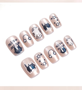 Flat lay of 10pc champagne cat-eye press-on nails with cute black cat and star designs
