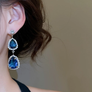 Close-up of elegant silver earrings with blue teardrop stones and sparkling crystals