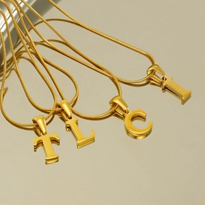 Detail of four gold 26-letter necklaces on snake chains featuring T, L, C, and I pendants