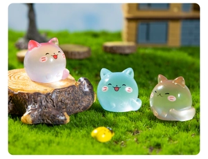 Detailed macro view of luminous resin mini cat figurines on miniature grass setup