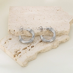 Détail macro de boucles d'oreilles géométriques argentées avec des strass étincelants