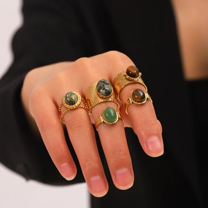 Set of 5 vintage stainless steel rings with tiger eye and green stones on a model hand