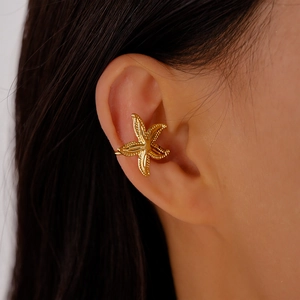 Close-up of a gold starfish-shaped ear cuff with textured metal detail on model ear