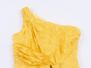 Close-up detail of yellow jacquard fabric texture and ruffled shoulder design of the dress