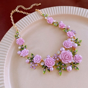 Detail of pink resin roses and green enamel leaves necklace with pearls and crystals