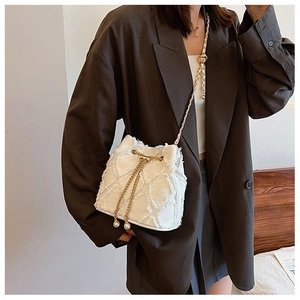 Detail of white tweed bucket bag with gold chain strap and pearl pendant on a model