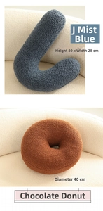 Close-up of J-shaped fog blue and donut-shaped brown plush pillows in soft sherpa fabric